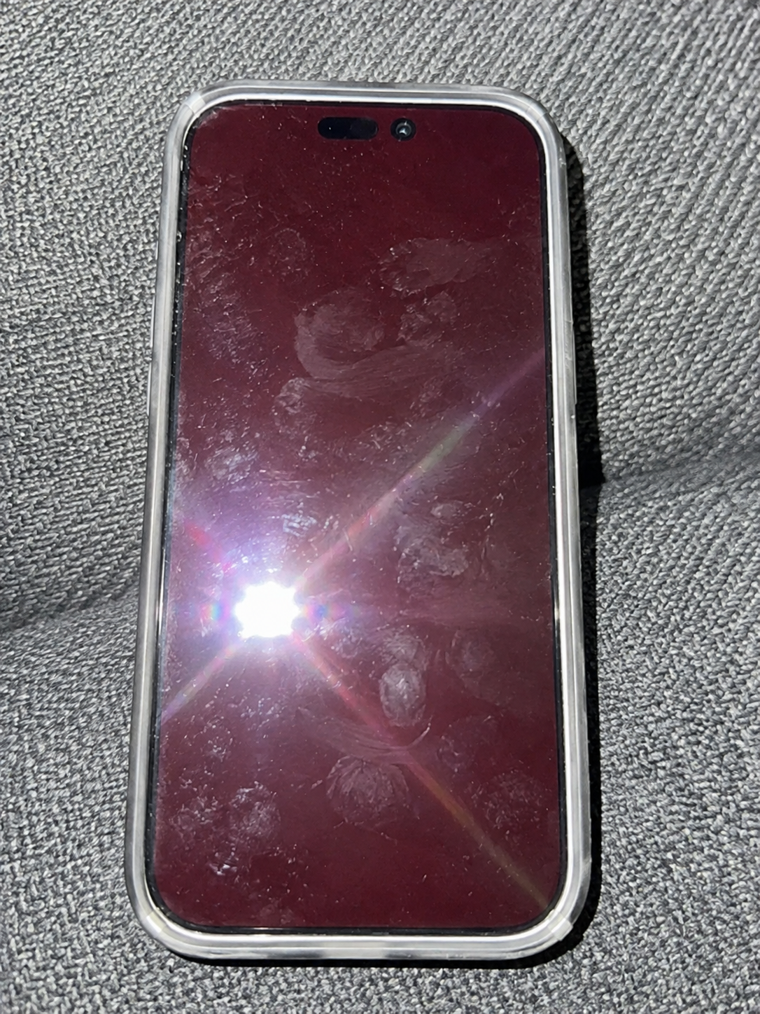 iPhone met LumaShield screenprotector op een lichte ondergrond met rode schermgloed.