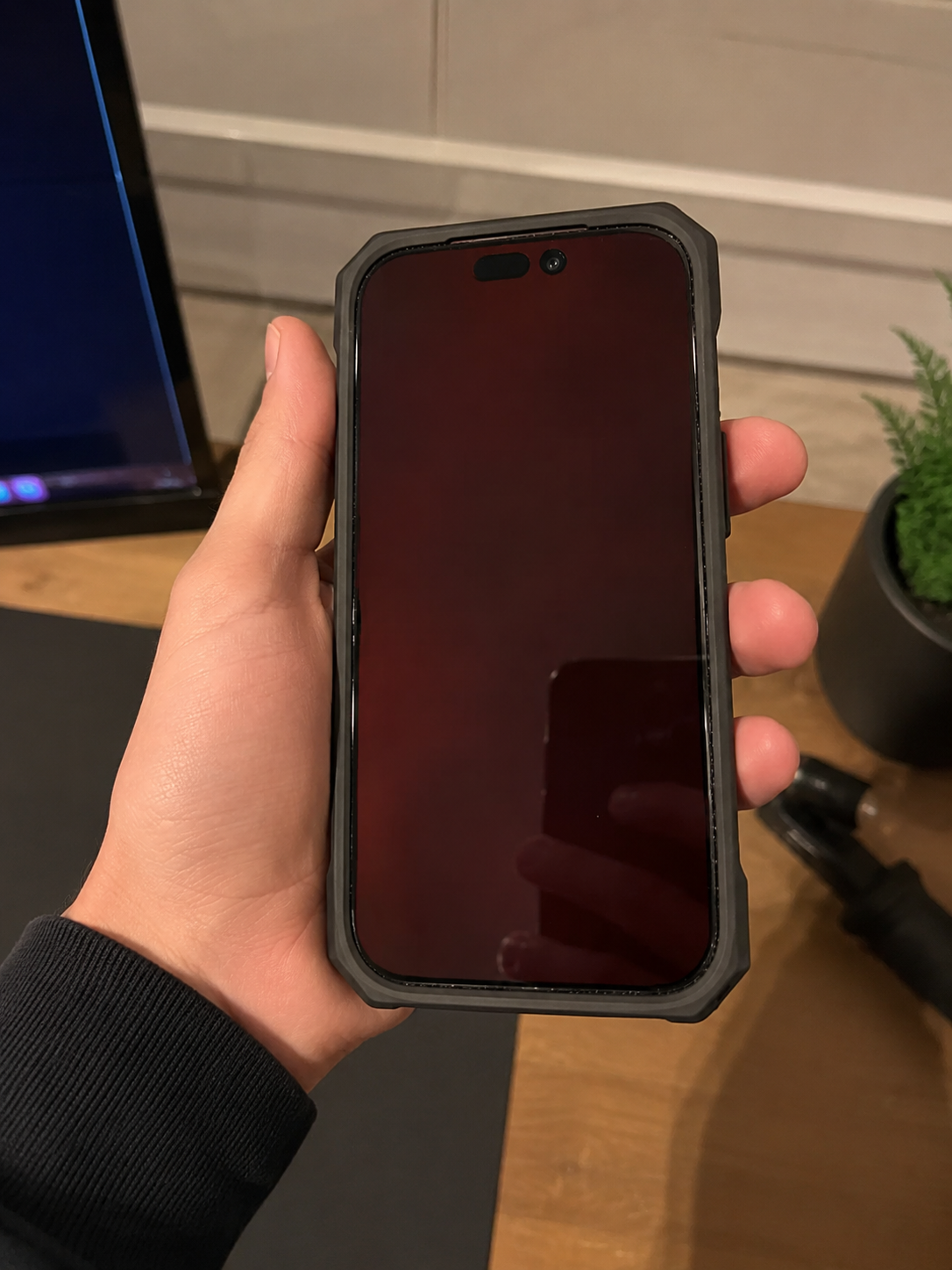 iPhone in de hand met LumaShield screenprotector en zachte rode schermweergave.